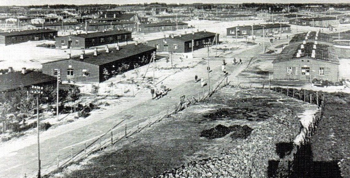 Historisches schwarz-weiß Foto. Luftaufnahme. In der Mitte ein Weg, links und rechts einstöckige Baracken.