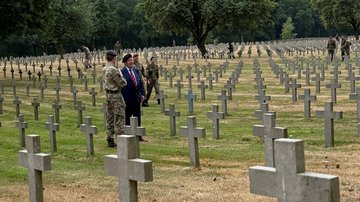 Soldaten stehen zwischen den Grabkreuzen und unterhalten sich 