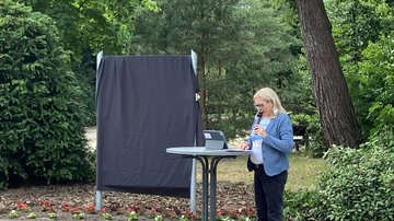 Bürgermeisterin Petra Gerlach am Rednerpult rechts vor der verhüllten Infotafel.