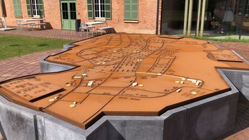 Im Vordergrund eine große Platte. Sie zeigt einen Plan des ehemaligen Lagers.