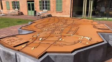 Im Vordergrund eine große Platte. Sie zeigt einen Plan des ehemaligen Lagers.